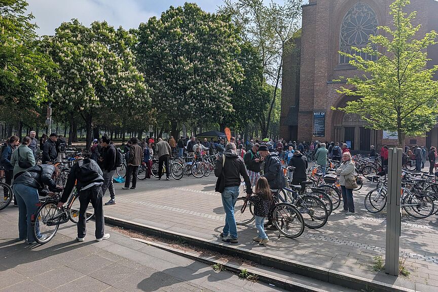 Bild vom ADFC-Gebrauchtfahrradmarkt vor der Kirche, zu sehen viele Menschen m, die Räder kaufen, verkaufen, begutachten