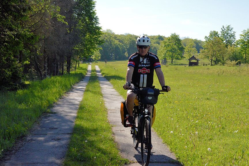 Person auf Rad mit Packtaschen durch Natur fahrend