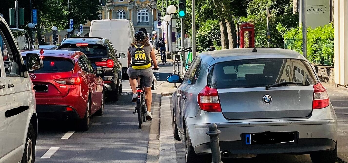 Foto vom Autostau auf der Adenauerallee mit einem an den Rand gedrückten Radfahrenden