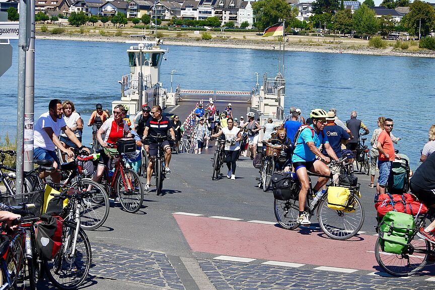Viele Fahradfahrende fahren von bzw. auf eine Fähre über den Rhein