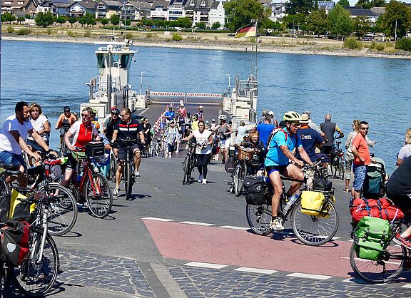 Viele Fahradfahrende fahren von bzw. auf eine Fähre über den Rhein 