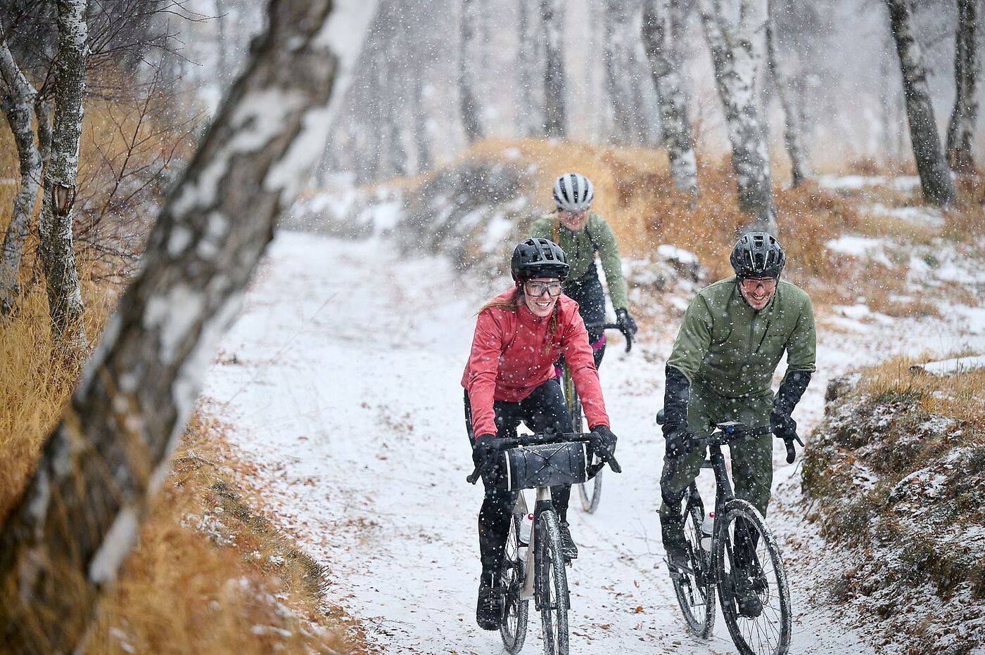 Eine Frau und zwei Männer fahren im verschneiten Wald. 